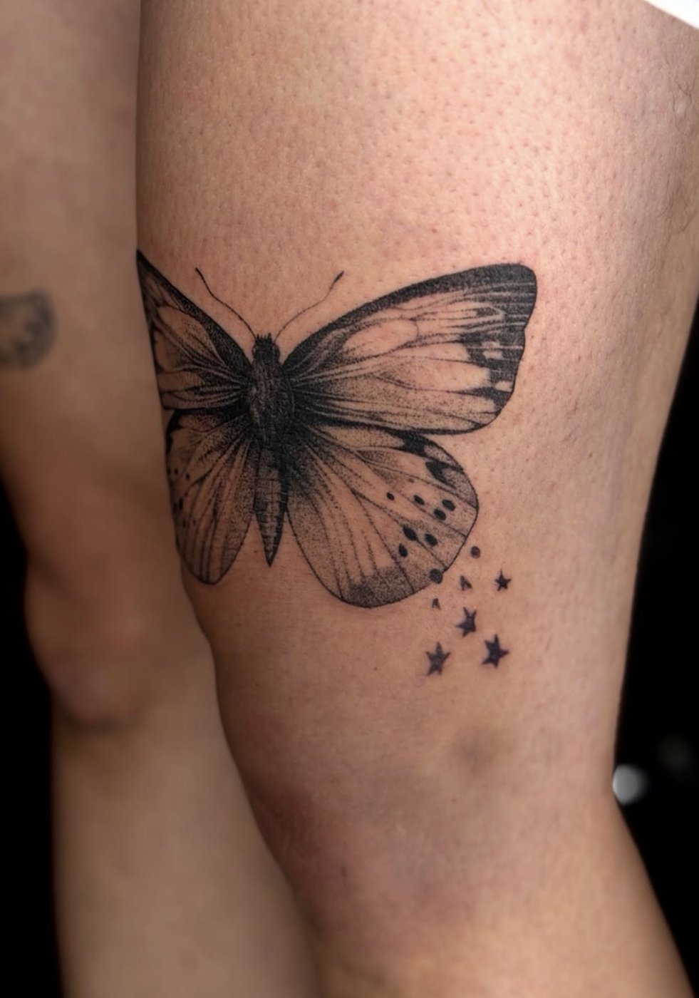Schmetterlings-Tattoo mit kleinen Sternen am Oberschenkel, gestochen von Florian Rudolph in Berlin