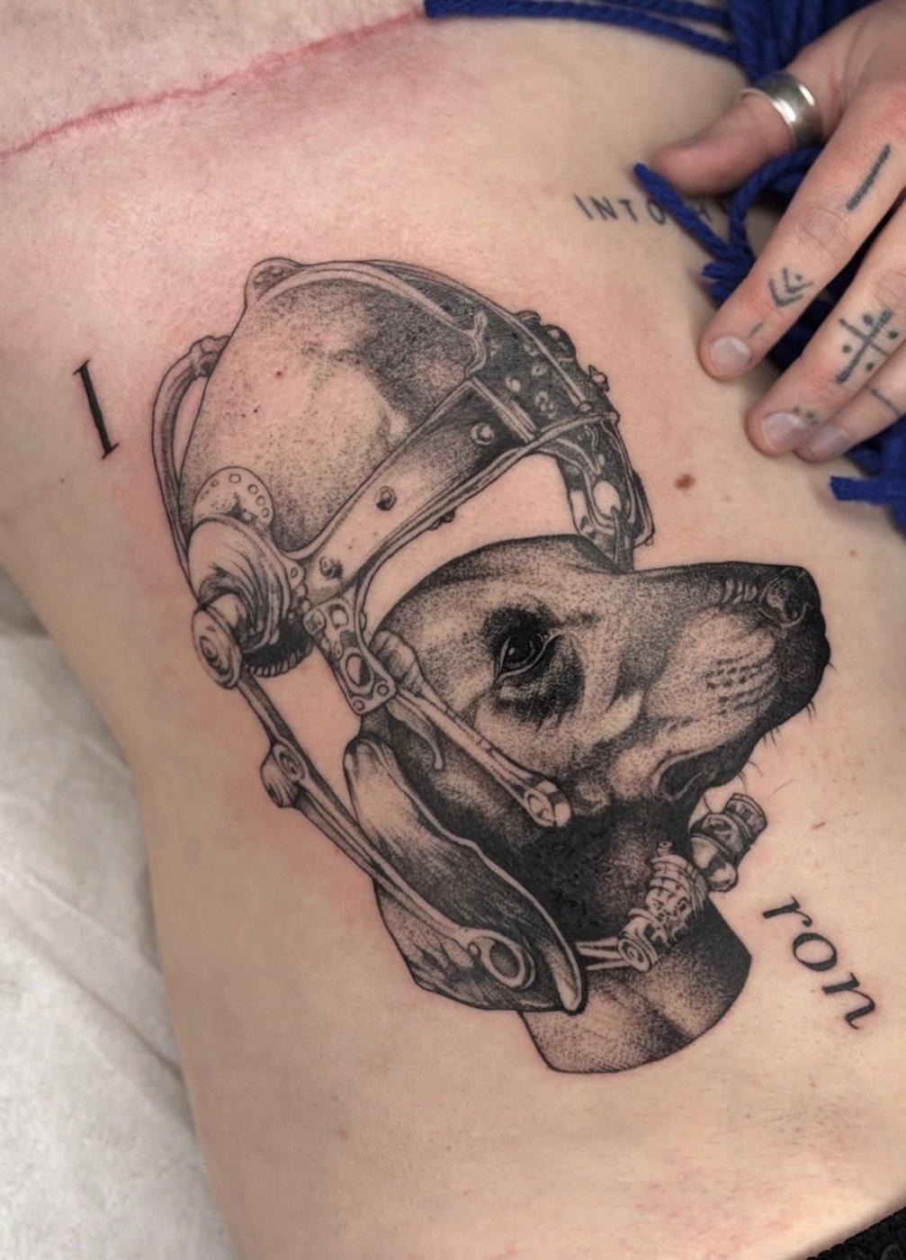 Surreales Tattoo am Oberschenkel: Hundekopf mit Gesichtsmaske aus Metall – gestochen von Florian Rudolph in Berlin