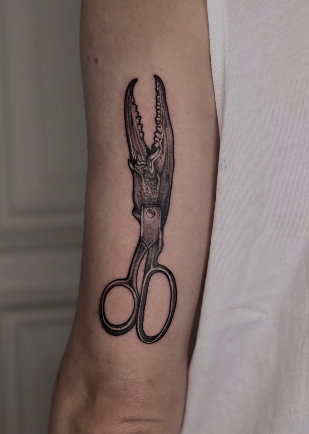 Surreales Tattoo am Unterarm: Schere mit Krebsschere als Klinge – gestochen von Florian Rudolph in Berlin